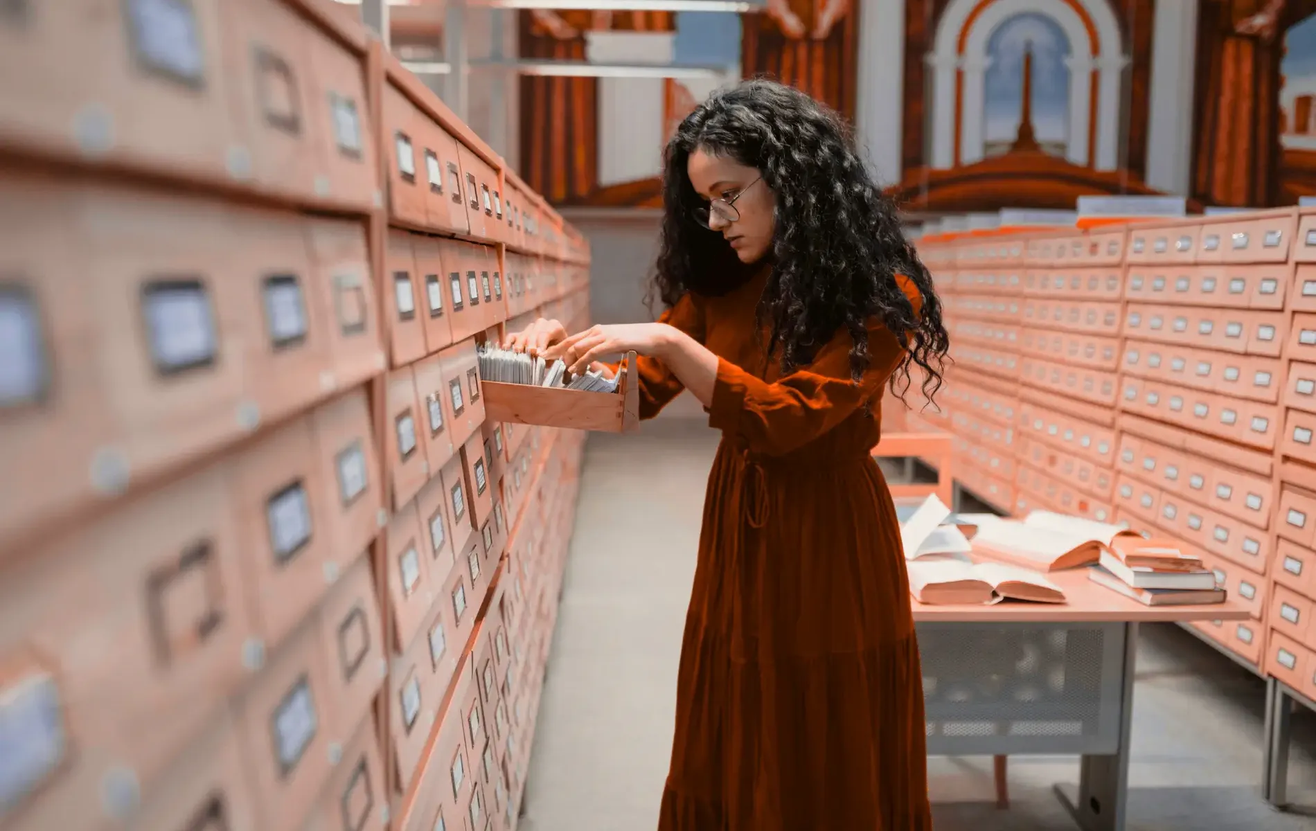 Person durchsucht eine Schublade in einem großen analogen Archiv, um Dokumente zwischen vielen Karteikästen zu finden