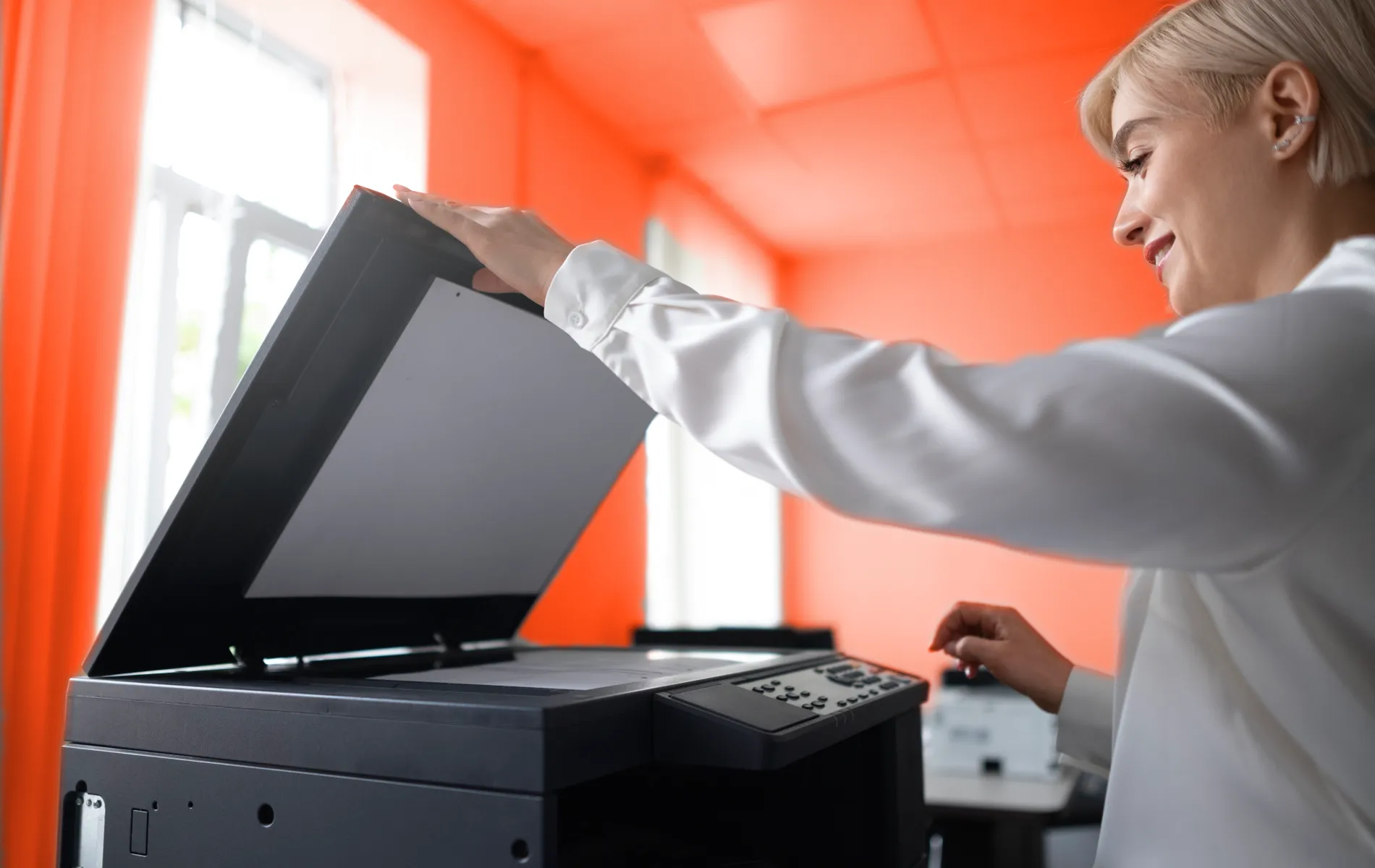 Frau scannt Dokument in Drucker im Büro