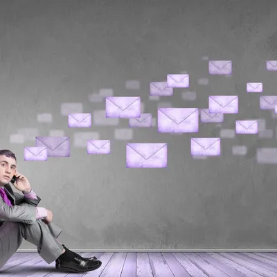 Geschäftsmann sitzt am Boden, während viele digitale Briefumschläge an ihm vorbeifliegen, symbolisiert E-Mail-Flut.