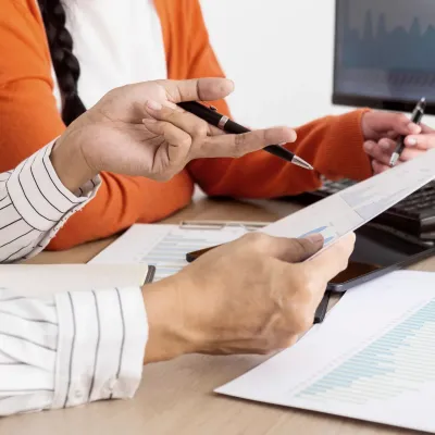 Two people analyzing business documents and charts at a desk