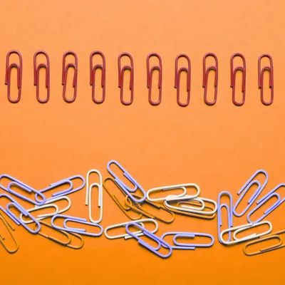 Wissensmanagement-Konzept dargestellt durch geordnete Büroklammern im Kontrast zu chaotischem Haufen