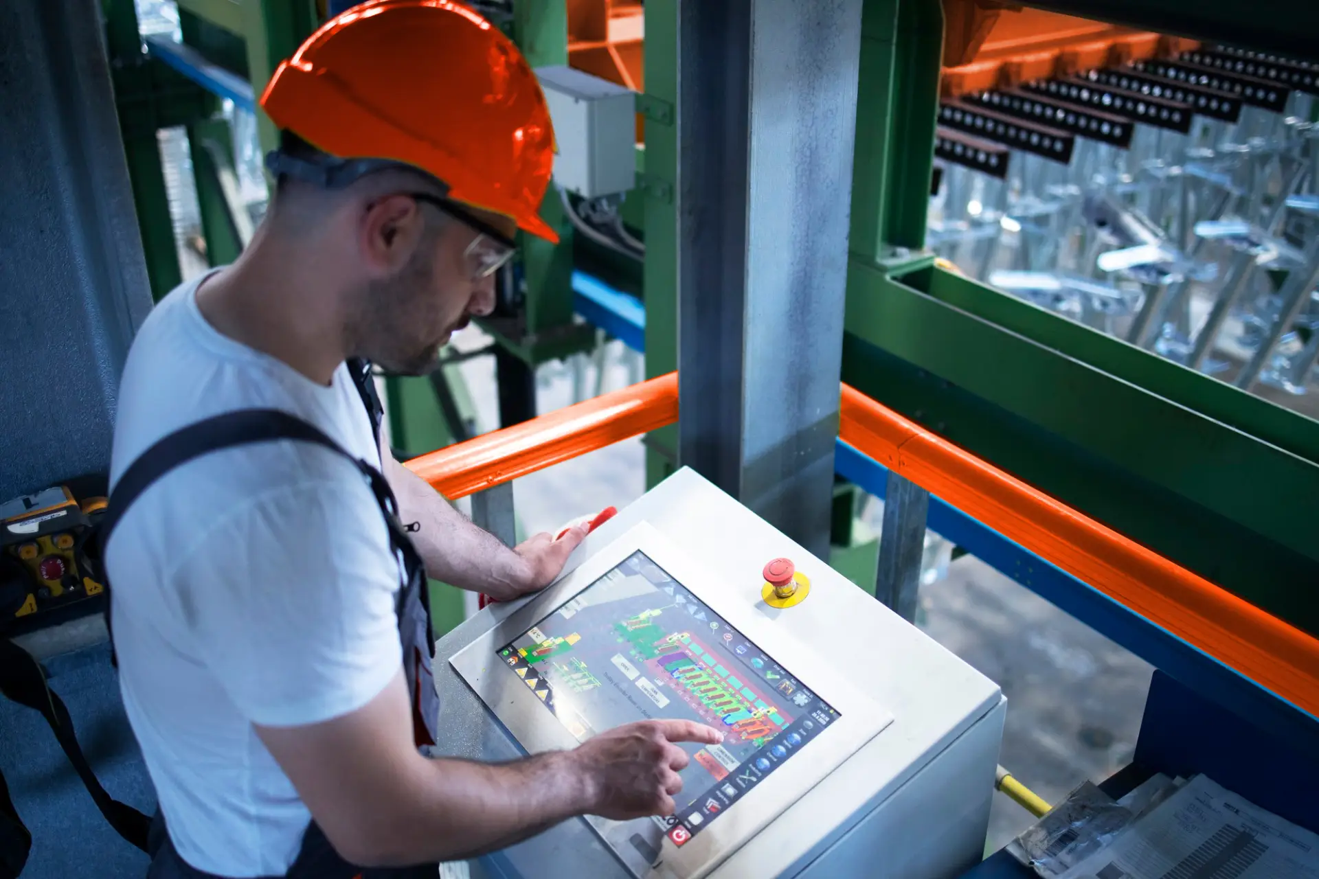 Arbeiter steht an einem Bildschirm in einer Iot vernetzten Fabrik.