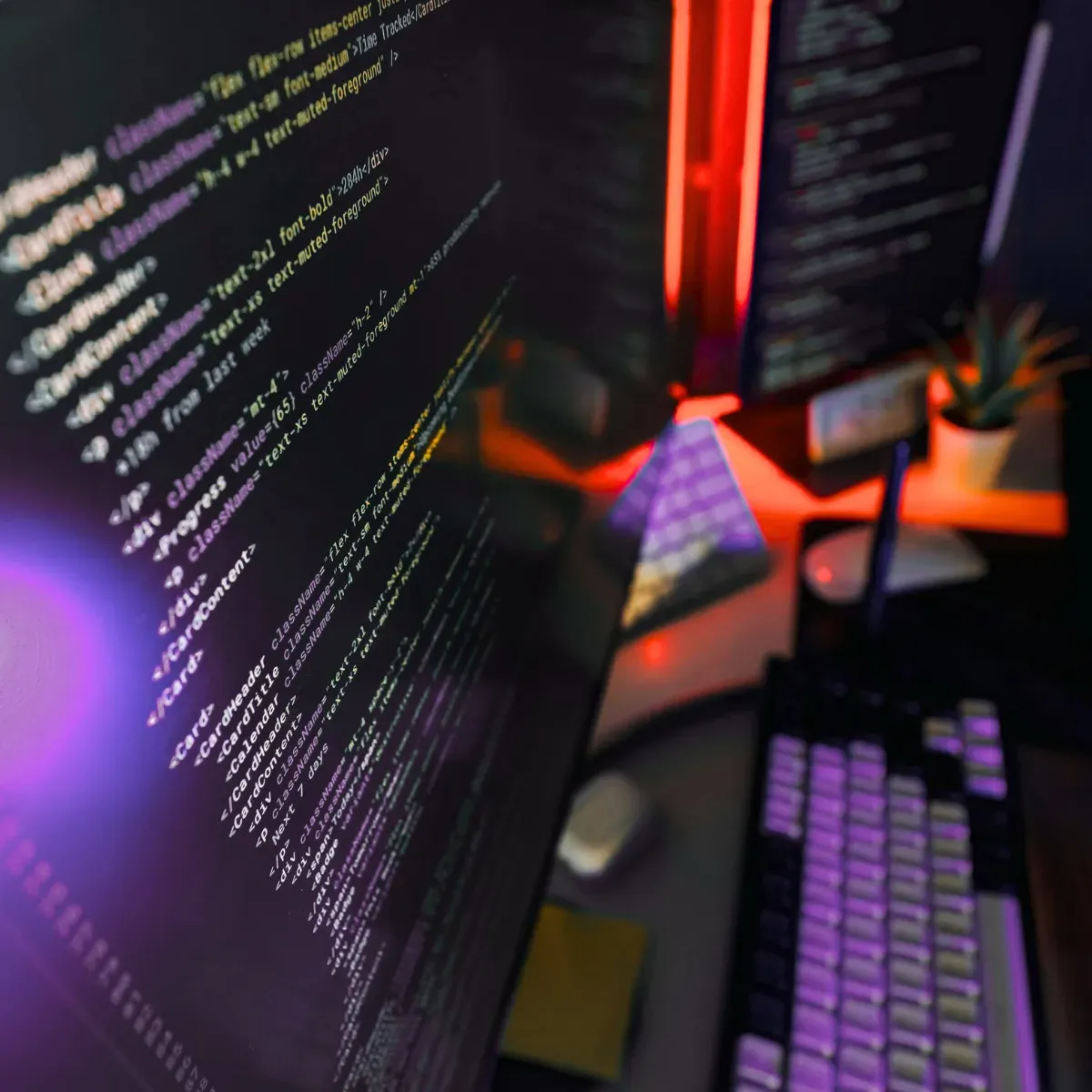 Close-up of a monitor displaying code with colorful neon reflections in a developer environment