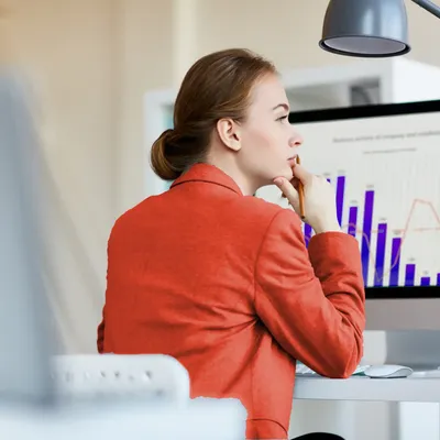 Eine Frau in einer roten Jacke studiert ein Diagramm am Computer.