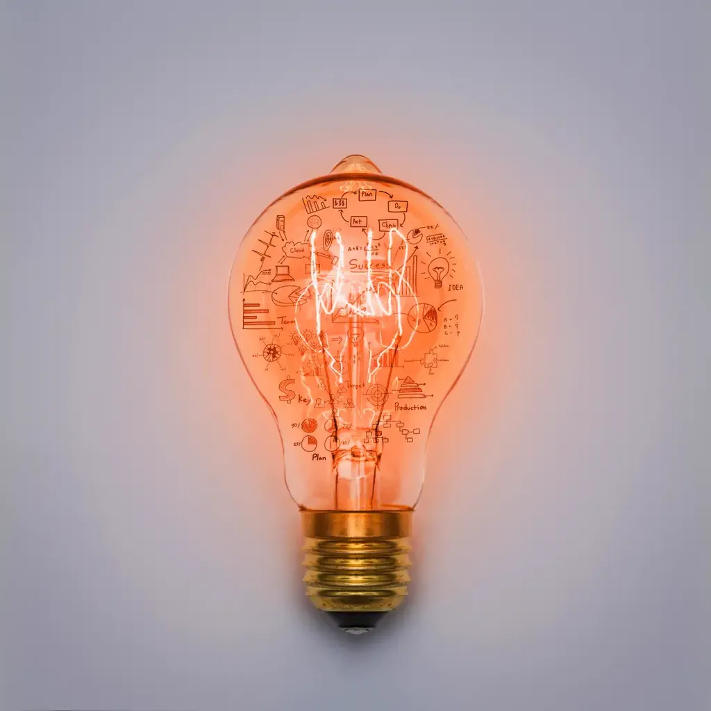Eine leuchtende Glühbirne mit darauf gezeichneten Geschäftsstrategie-Diagrammen.