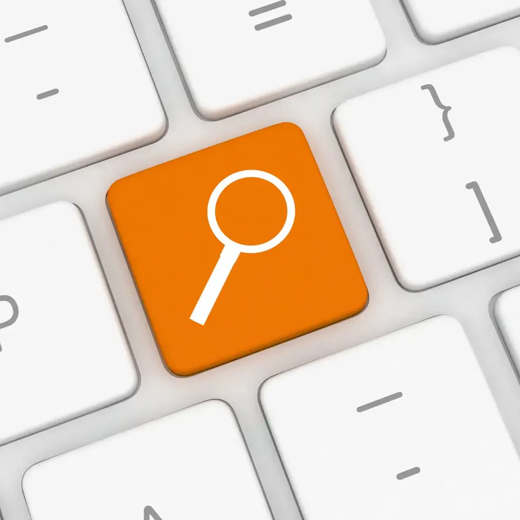 Eine orangefarbene Tastaturtaste mit einem weißen Lupensymbol.