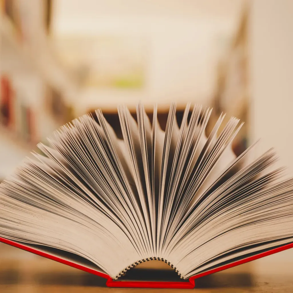 Ein aufgeschlagenes Buch mit rotem Einband und aufgefächerten Seiten.