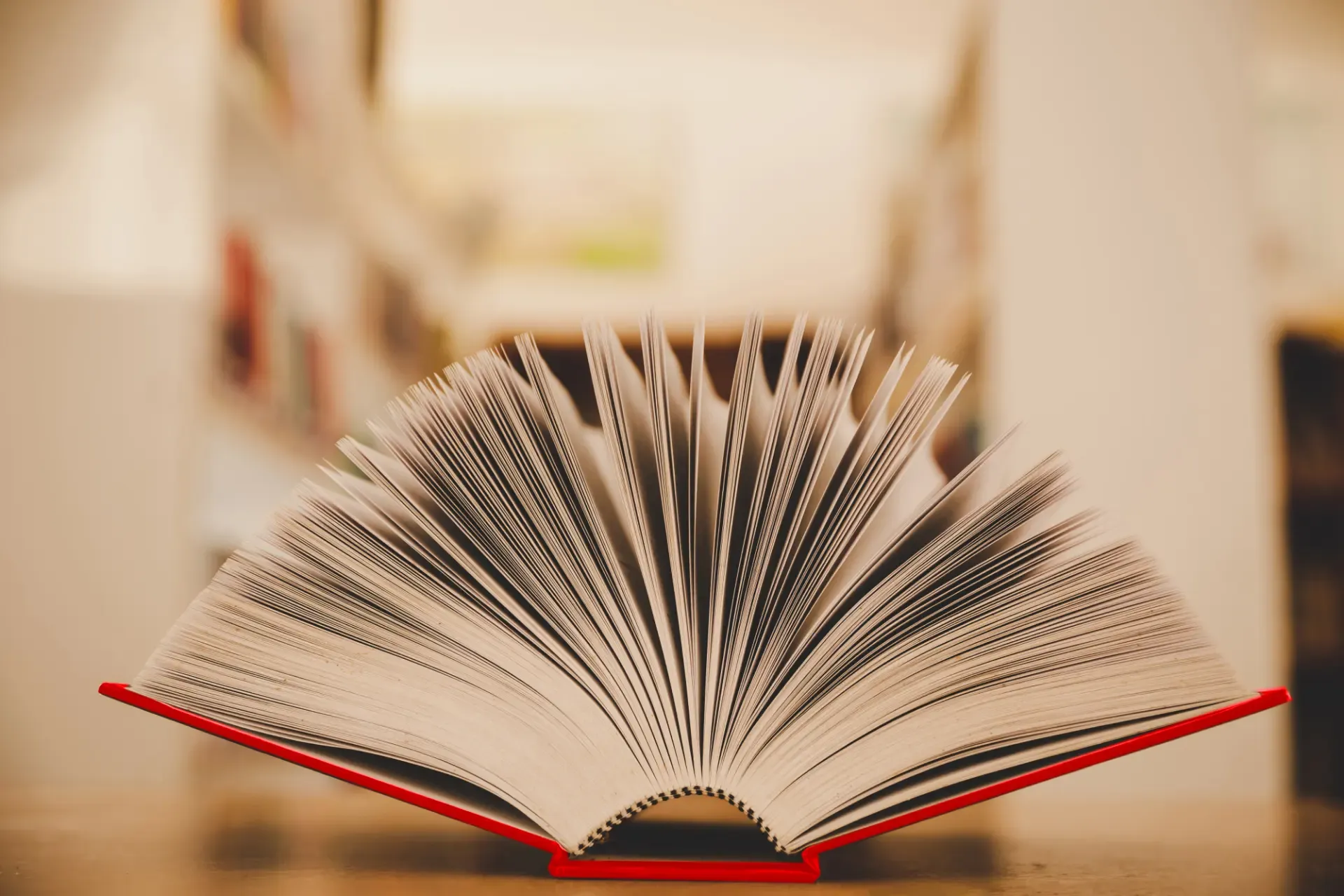 Ein aufgeschlagenes Buch mit rotem Einband und aufgefächerten Seiten.