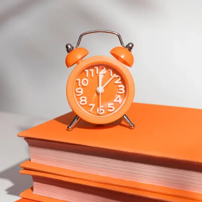 Oranger Retro-Wecker auf Büchern