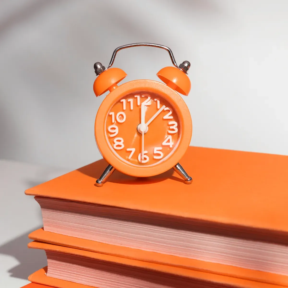 Oranger Retro-Wecker auf Büchern