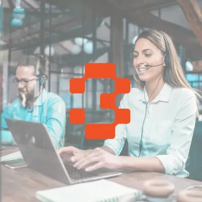 Zwei Mitarbeitende im Kundenservice arbeiten am Laptop mit Headset, orangefarbenes Icon im Vordergrund