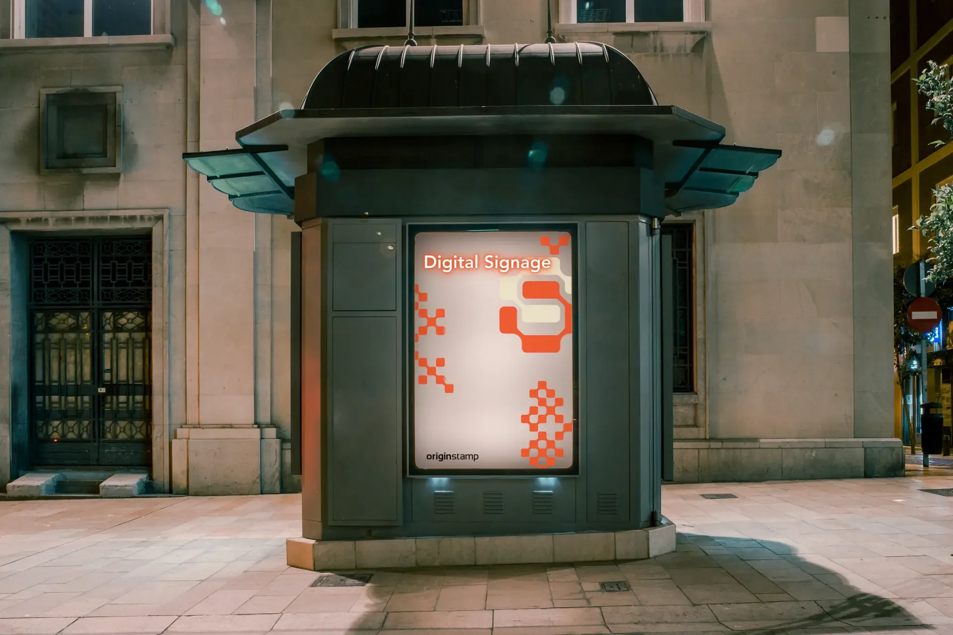 A digital signage kiosk on a city sidewalk at night.