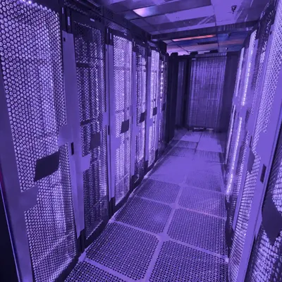 Moderner Serverraum mit beleuchteten Rack-Reihen und violettem Licht.
