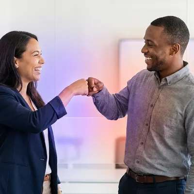 Two smiling colleagues fist-bumping in an office with abstract digital network overlays.